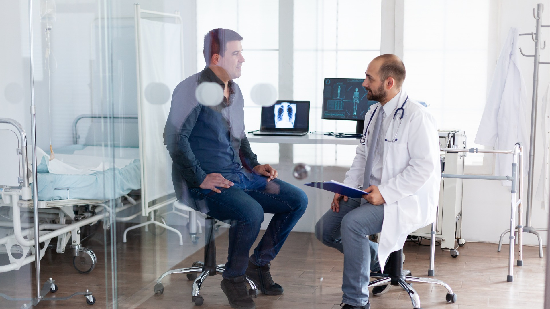 doctor-consulting-young-man-hospital-examination-room-wearing-white-coat